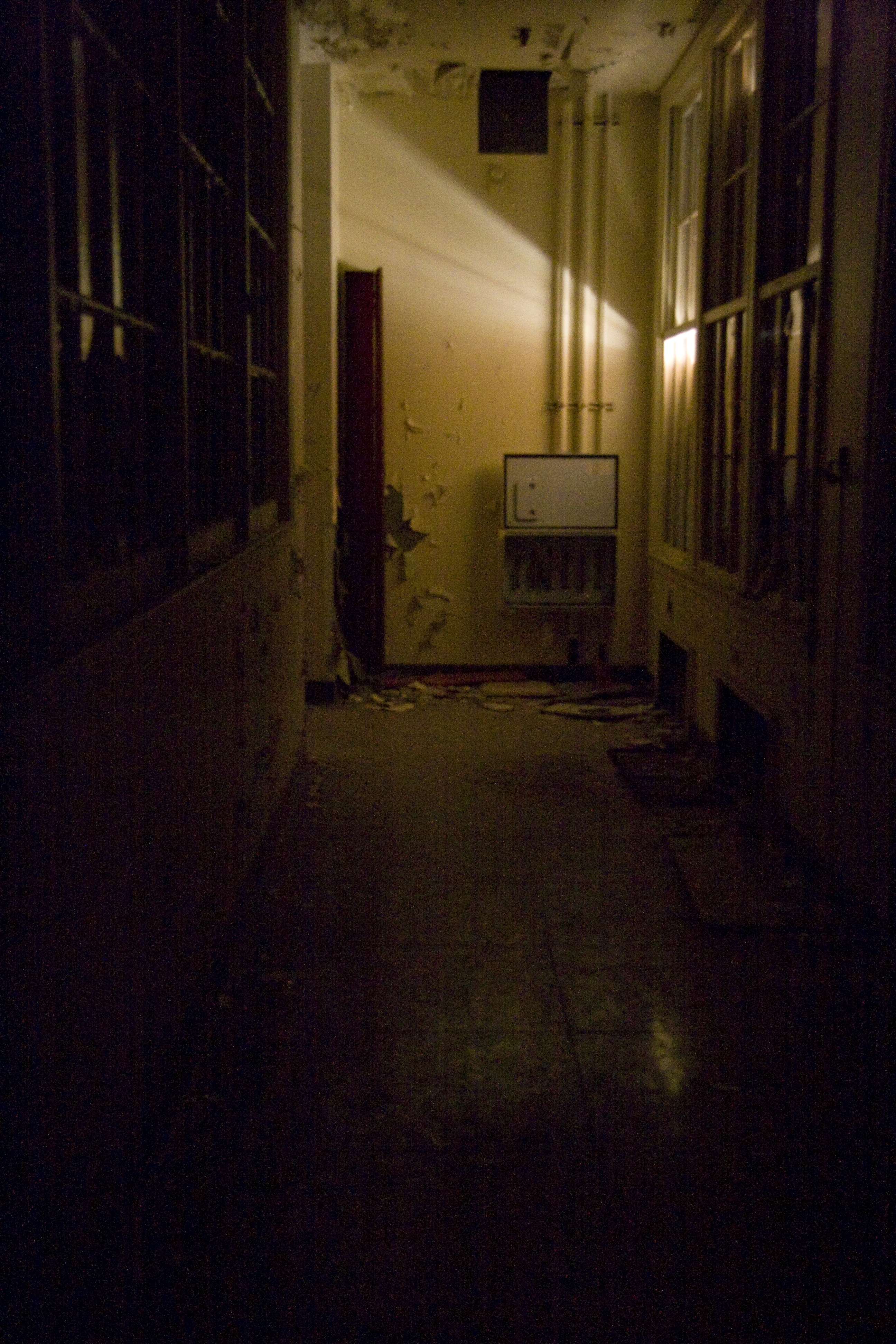 LIGHT ENTERS - a tiny hole in the wall barely provides minimal illumination in this dim corridor.